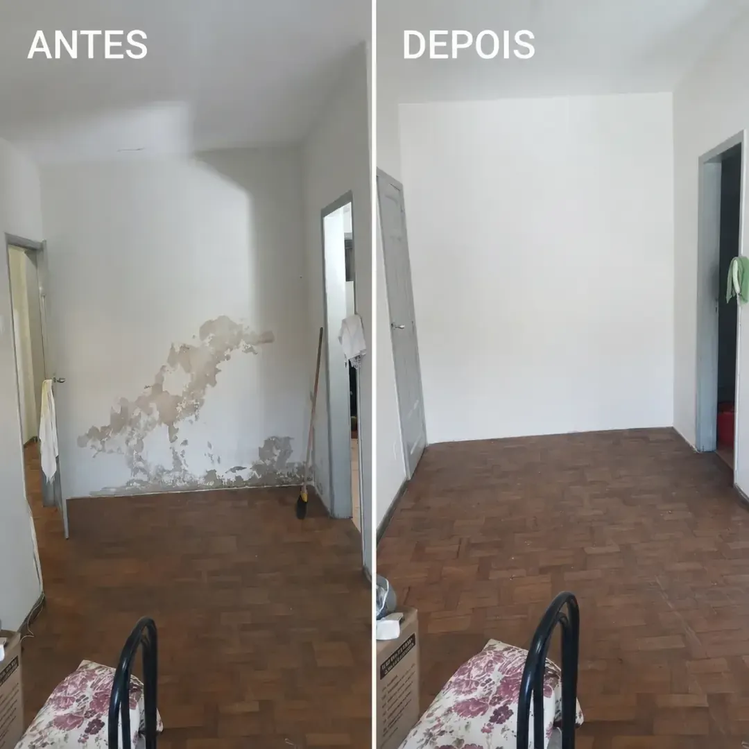 Recuperação de parede com infiltração. Parede de quarto com massa descolada e mancha de umidade na base. Raspagem da área comprometida, correção e repintura, com o rodapé e o piso preservados.
